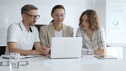 Obraz premium Business people team collaborating on a project, analyzing data on a laptop during a productive office meeting