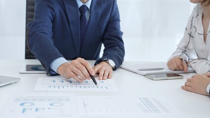 Business team engaging in a corporate meeting, discussing strategies while analyzing financial charts and graphs on a digital tablet alongside printed documents