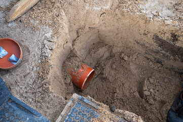 Excavated Construction Site with Exposed Orange PVC Drainage Pipe in Sandy Soil.