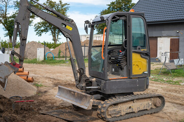 Compact Excavator at Residential Construction Site with Open Cabin and Track System.