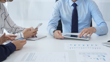 Business colleagues strategizing in modern workspace, reviewing financial analytics on digital devices, sharing insights through collaborative teamwork and data driven discussion