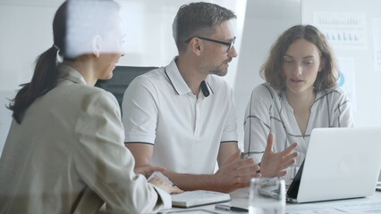 Fototapeta premium Professional team working together, reviewing digital analytics on laptop screen while strategizing corporate project details in modern workplace environment. Business people concept