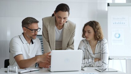 Fototapeta premium Business team collaborating on a project, analyzing data on a laptop during a productive office meeting, demonstrating teamwork and problem solving skills