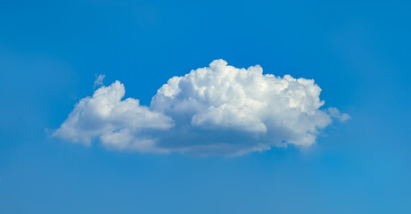 A broad cumulus cloud floats across the sky from left to right. The breath of nature against a pure blue background. Power rain, wind, elements. Swirling vapors rise dynamically threaten the world.