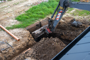 Excavator Digging Trench for Underground Pipe Installation at Construction Site.