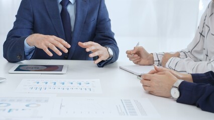 Business team collaborating in an office, analyzing financial data through digital tablets and documents during a meeting. Close up view of hands engaged in discussion and strategy planning