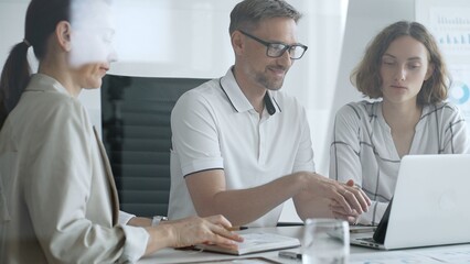 Business team collaborating and analyzing data on a laptop during a productive office meeting, discussing strategies and making informed decisions