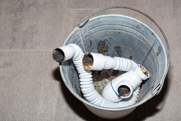 The bucket contains used, dirty PVC pipes, possibly removed during plumbing renovations