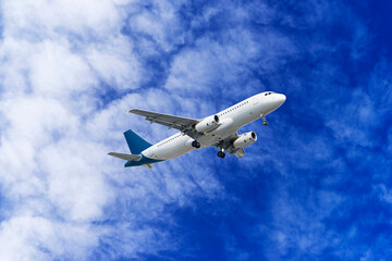 A passenger plane is flying in a beautiful blue sky with white clouds