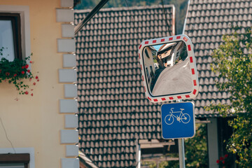 Traffic mirror and bicycle lane sign symbolizing road safety and navigation in a rural mountain village.