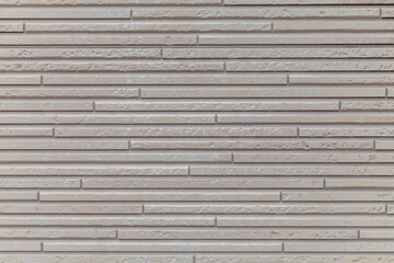 Wall with a pattern of brown and white lines. The wall is made of concrete and has a rough texture