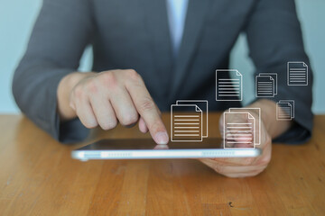 Businessman check report on tablet with digital document icons for online file management and cloud storage. Concept of data sharing, digital transformation, paperless office and business technology.