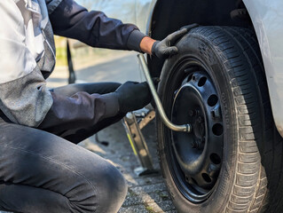 A man removing a car wheel during seasonal tire change. Concept of car service, vehicle maintenance, safety and transportation.