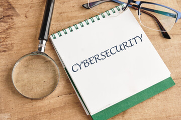 The concept of technology and development. Phrase, words, text CYBERSECURITY in a notebook on an old background, in a composition with a magnifying glass and glasses