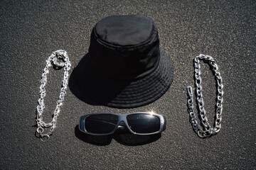 Stylish Black Bucket Hat, Sunglasses, and Silver Chains on Asphalt