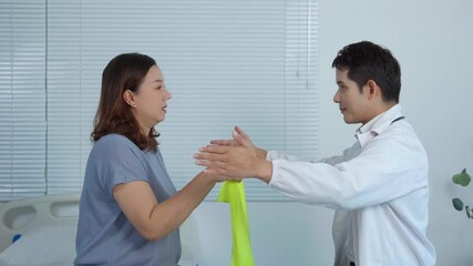 Professional physiotherapist guiding a female patient through arm exercises with a resistance band, focusing on rehabilitation and recovery in a clinical setting - Powered by Adobe