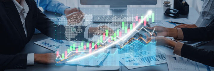 A business team collaborates on financial growth strategies using digital graphs and charts in a modern office. The scene captures teamwork and innovation. Axiom