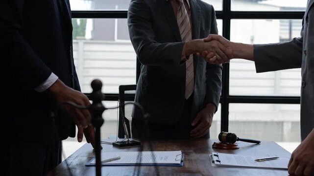 Legal professionals celebrating successful partnership, shaking hands after signing contract in modern office setting, symbolizing collaborative achievement and professional agreement