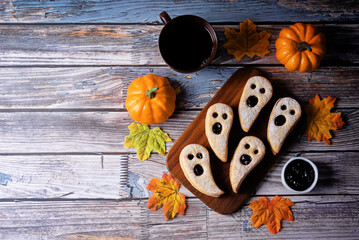 Linzer cookies in the form of ghosts for Halloween holidays on a wood background