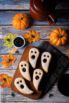Linzer cookies in the form of ghosts for Halloween holidays on a wood background