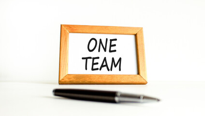 One team symbol. Concept word One team on beautiful wooden picture frame. Black pen. Beautiful white paper background. Business one team concept. Copy space.