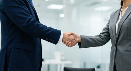 Business handshake between two people in an office setting.