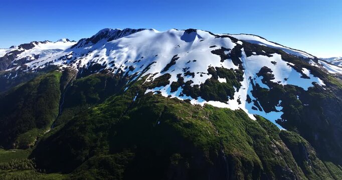 Striking scenery of beautiful verdant mountains with snow on top. Drone footage of the stunning rocks in Alaska, USA.