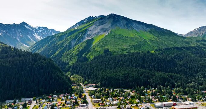 Beautiful urban landscape surrounded by the pine tree woods growing on the mountains. Rising over the residential area in Alaska, USA.