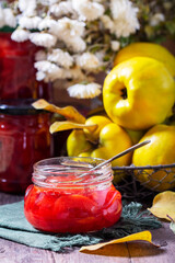 Quince jam in a glass jar, quince in a basket and a bouquet of chrysanthemums. Autumn still life.