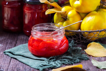 Quince jam in a glass jar, quince in a basket and a bouquet of chrysanthemums. Autumn still life.