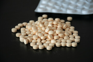 A close-up view of assorted medical tablets on a dark surface, illustrating health, self-medication, and pharmaceutical concepts for seasonal illnesses and treatments.