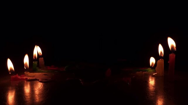 Glowing colorful candles burns softly in the dark night, its gentle flame reflecting on the floor, spreading warmth, peace, and romance during a holiday celebration at the church.