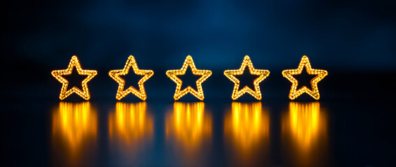 Five golden stars in a row,  glowing on a dark blue background.