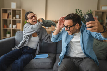 Couple having fun pillow fight making selfie video