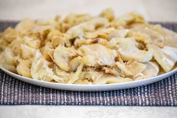 chips of gadus macrocephalus cod fillet, salted and dried, on a round white plate