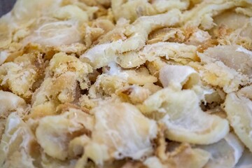 chips of gadus macrocephalus cod fillet, salted and dried, on a round white plate