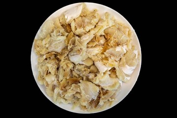 chips of gadus macrocephalus cod fillet, salted and dried, on a round white plate