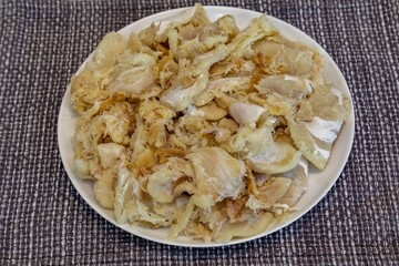 chips of gadus macrocephalus cod fillet, salted and dried, on a round white plate