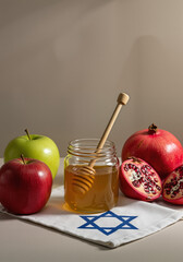 Jar of honey with apples and pomegranates on Star of David cloth for Hanukkah  