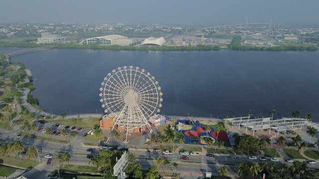 Aerial view of a Ferris wheel near Laguna del Carpintero in Tampico during calm sunrise with peaceful water and clear sky