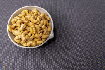 Bowl of cashew nuts on gray background