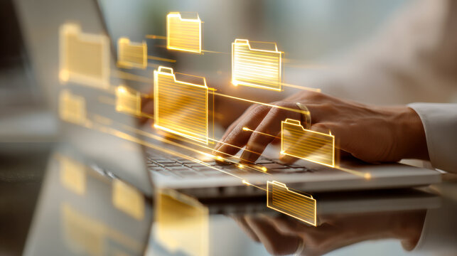 Person managing digital file organization with holographic yellow folders appearing above laptop keyboard in a modern office setting reflecting productivity and technolog