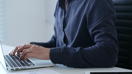 Professional businessman typing on laptop, surrounded by financial reports and digital tablet, working in contemporary corporate workspace. Business people concept - Powered by Adobe