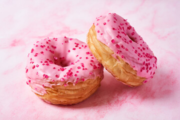 Two pink cronuts on pastel pink background