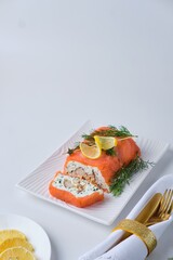 A cold appetizer, a terrine of salted salmon and smoked mackerel with cheese cream and dill, served on a white rectangular plate against a white background.