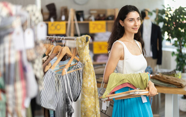 Woman on summer sale at a clothing store. Armenian woman stands in a boutique and holds hangers...
