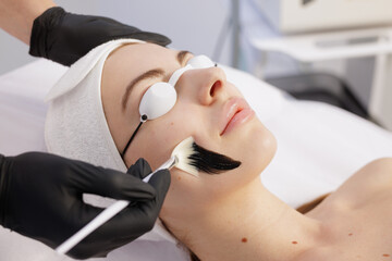 Charcoal peel application on face in professional spa clinic