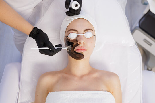 Charcoal peel applied with brush in clean spa clinic