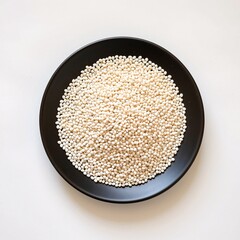 White Quinoa Grains Displayed on Round Black Plate Isolated Background
