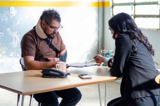 Young female lawyer assist a injured man with legal problem. Lawyer showing document. Compensation for work or car accident. Legal concept. Social Worker.